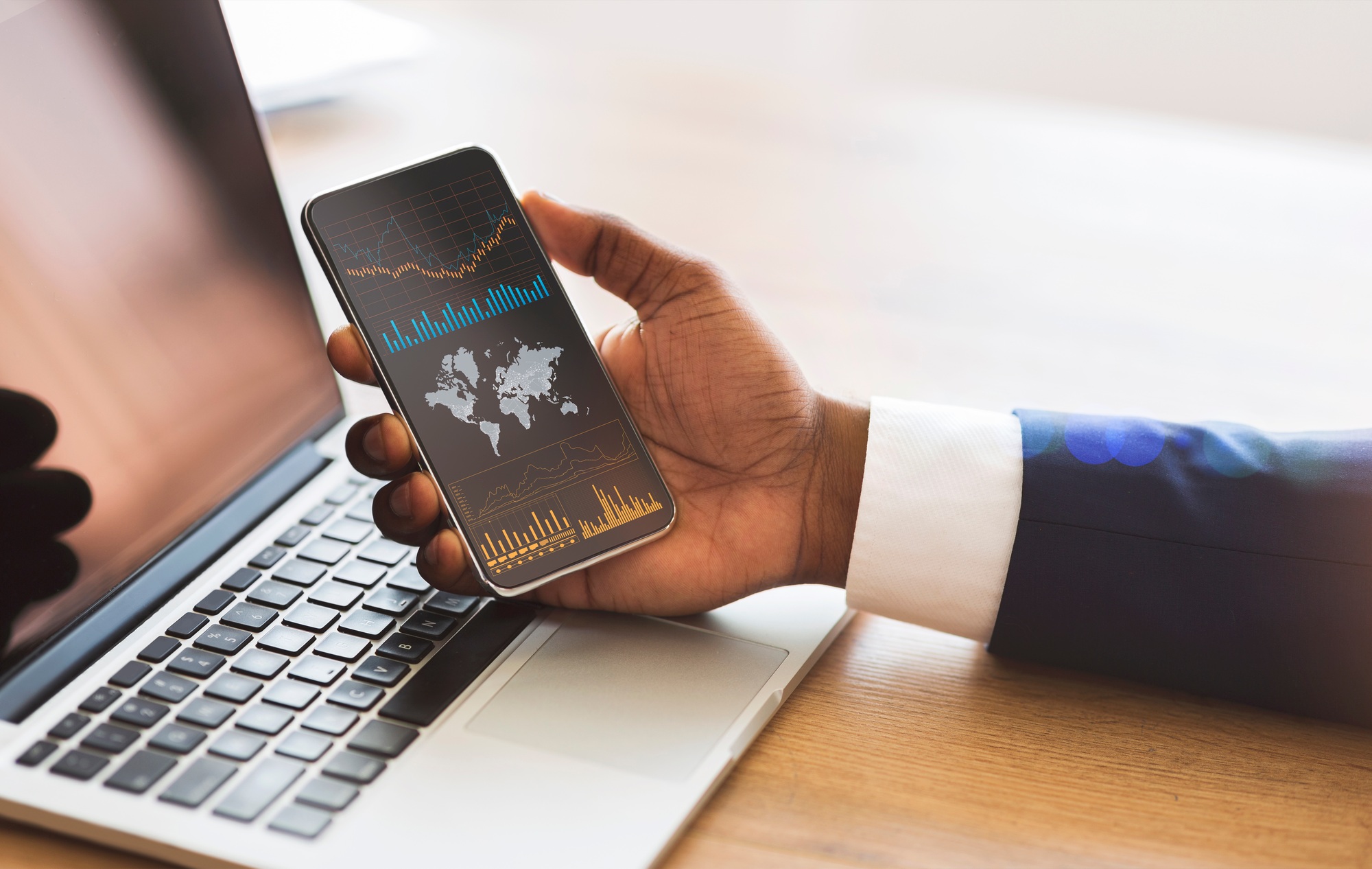 Black businessman checking global financial analytic on smartphone or trading on forex