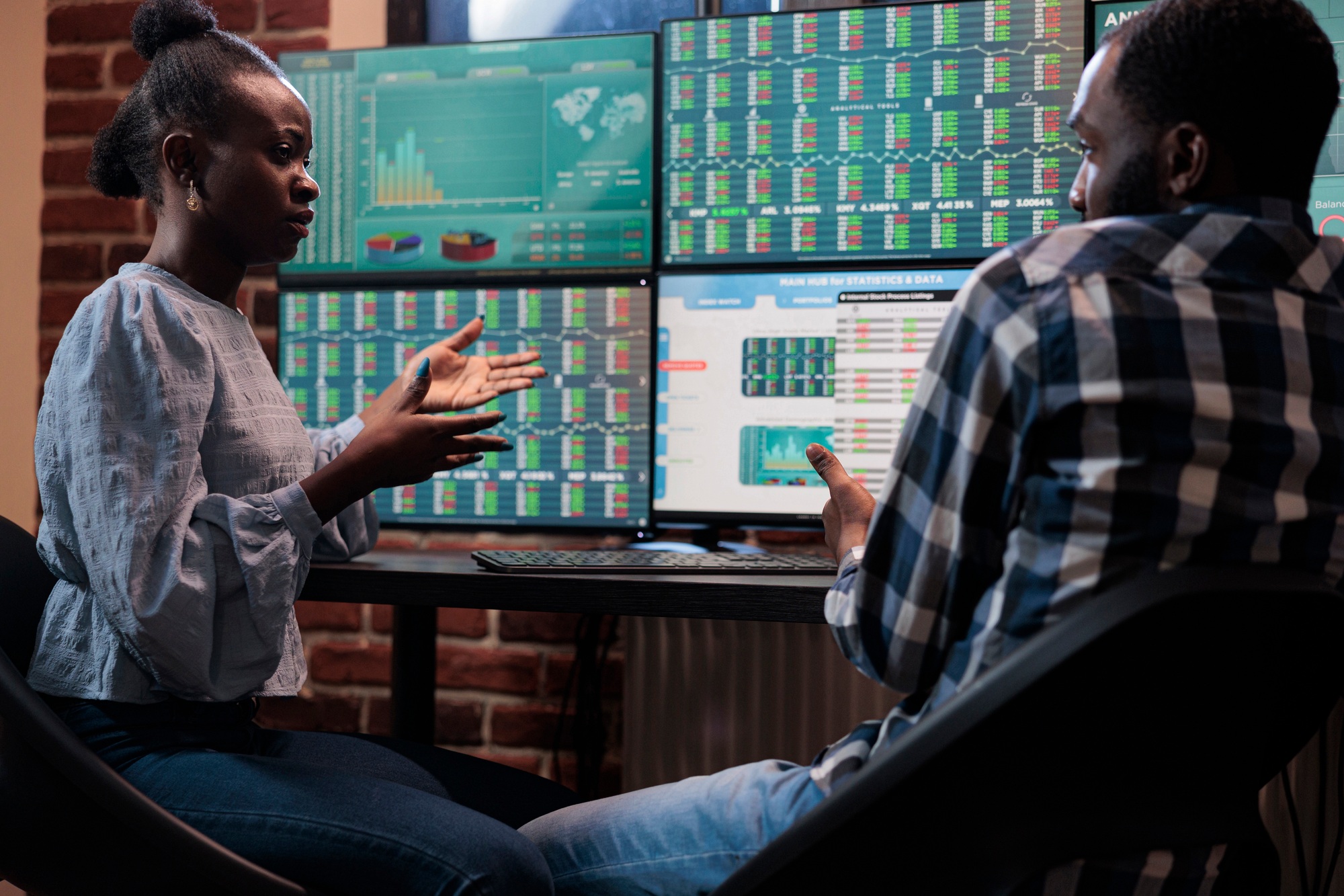 Investment company professional traders sitting at multi monitor workstation